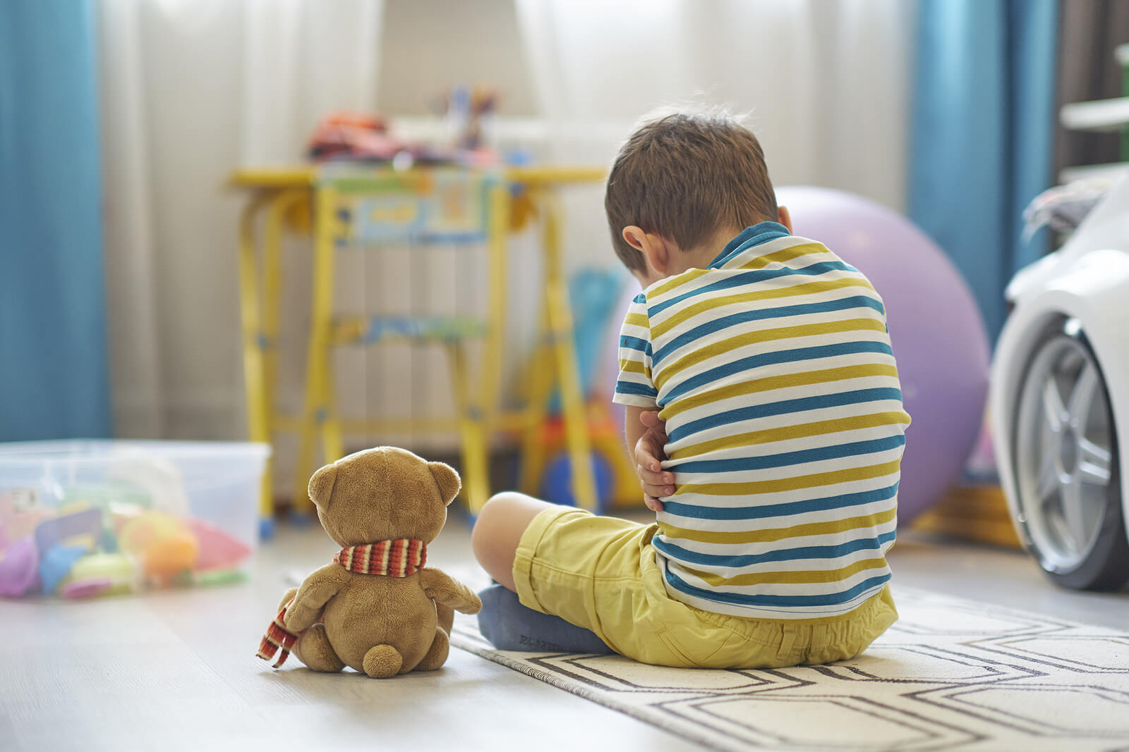 Bambino seduto sul pavimento che sta attraversando un disturbo da stress post-traumatico.