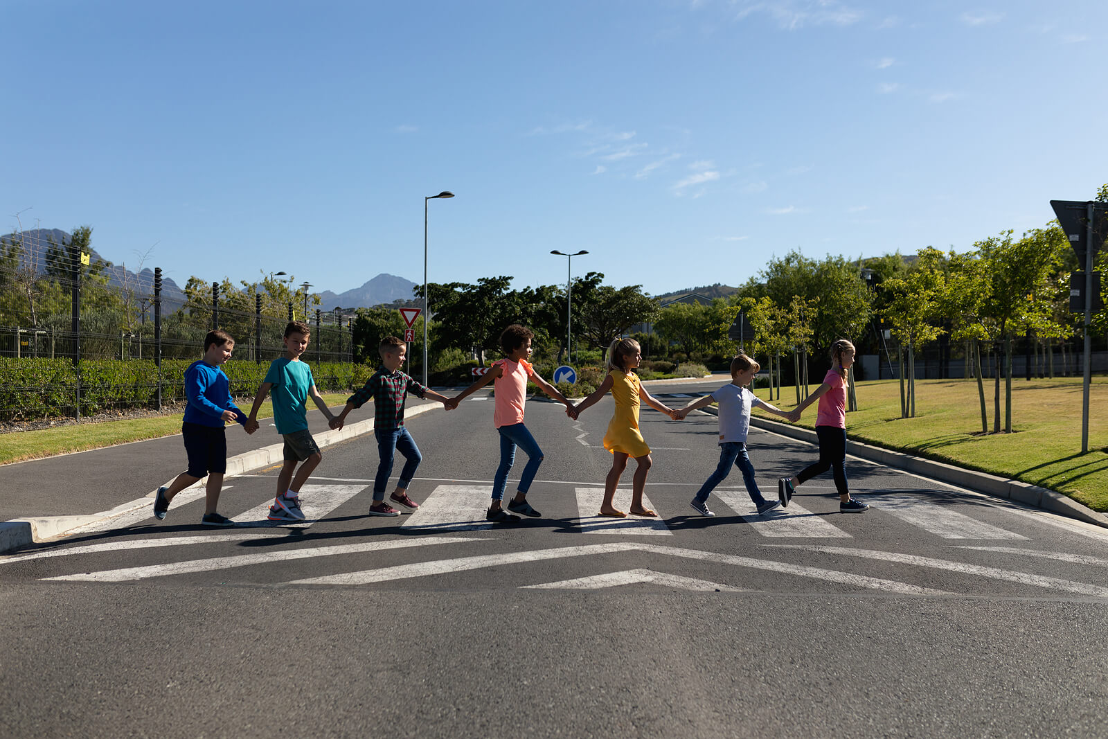Bambini mano nella mano che attraversano un passaggio pedonale.