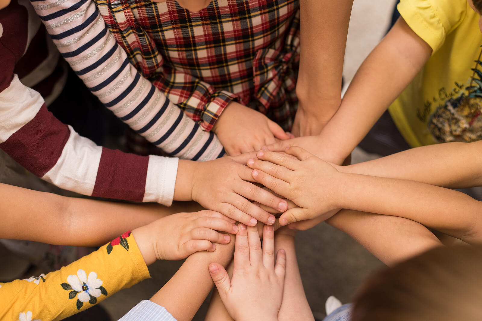 Niños uniendo las manos como equipo.