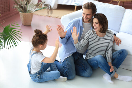 Padres jugando con su hija sentados en el suelo.