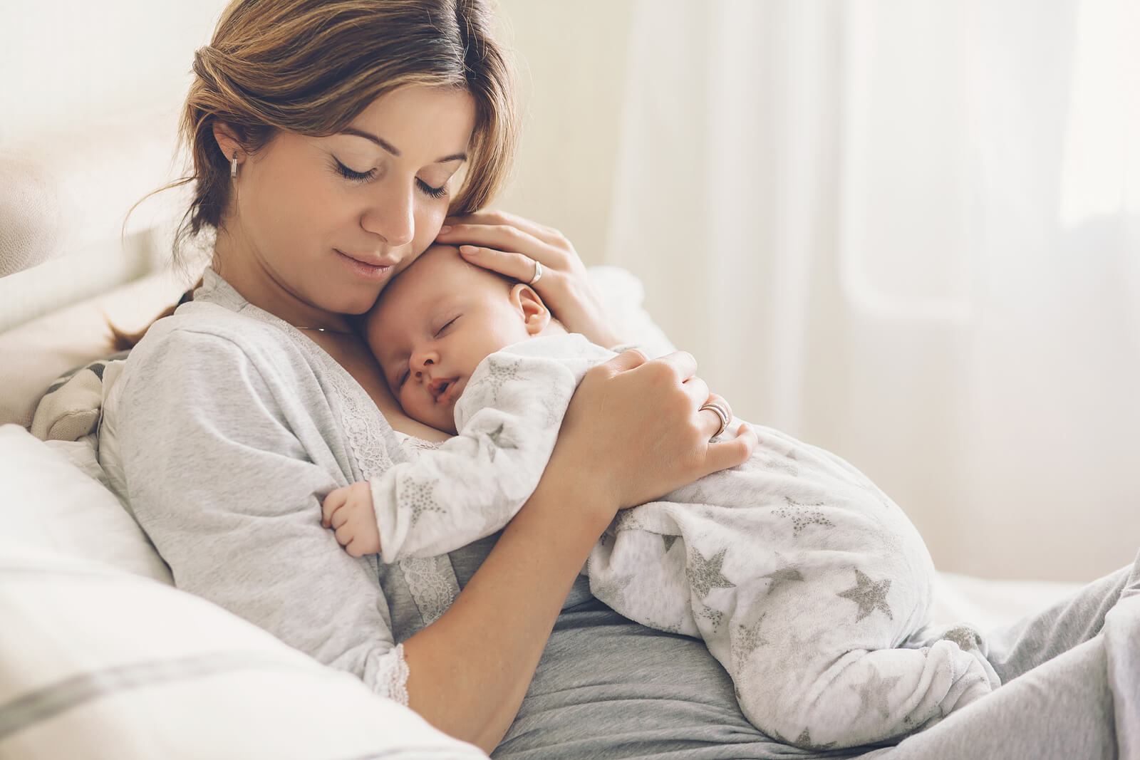 Madre abrazando a su bebé dormido en sus brazos.