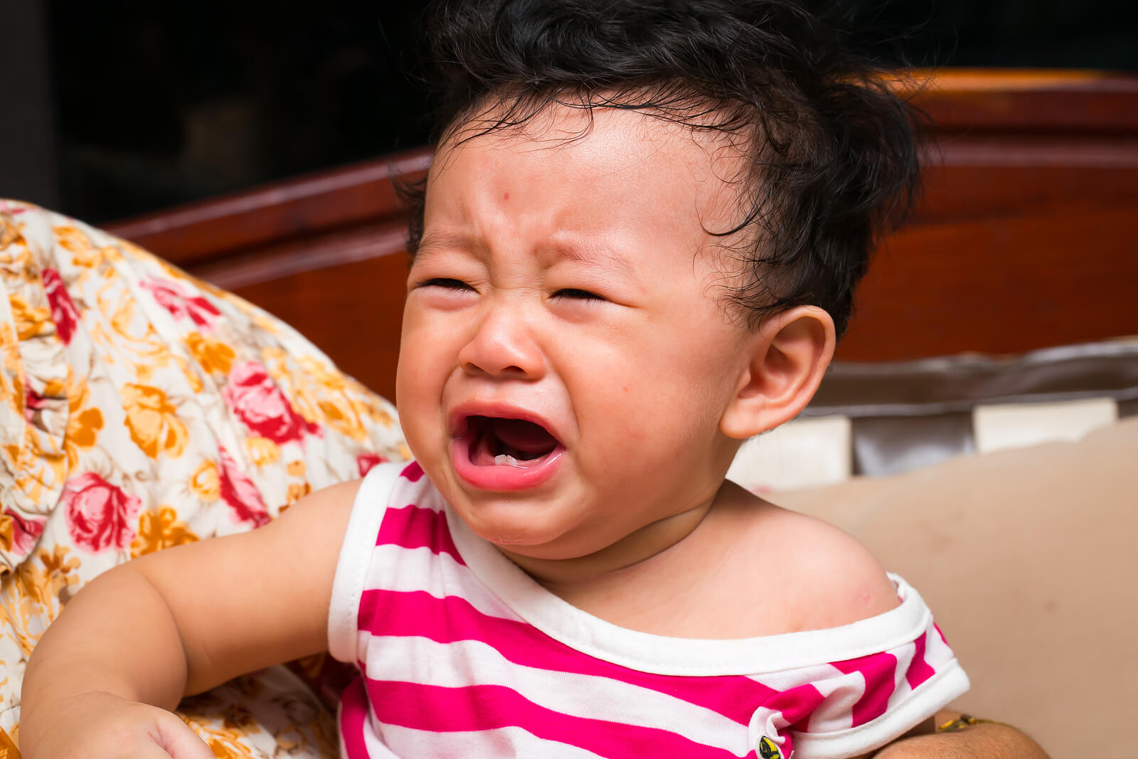 A baby with two bottom teeth crying.