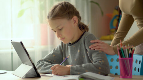 Madre apoyando a su hija mientras estudia en casa.