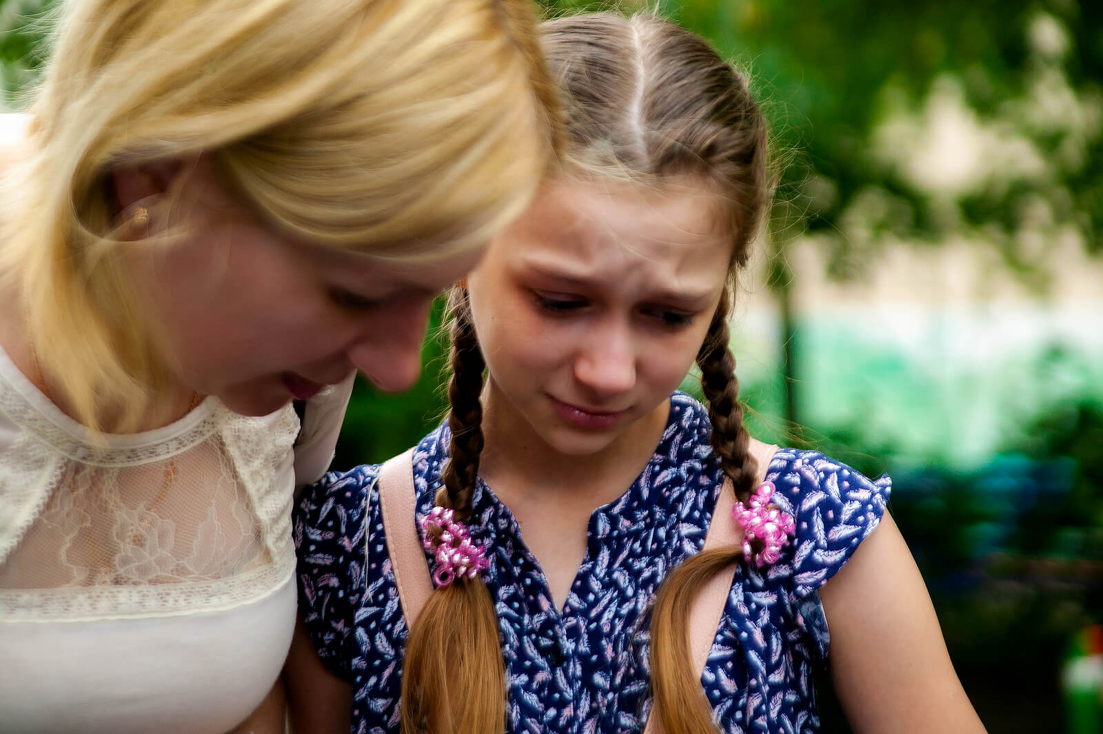  A crying teenage girl showing something to her mother.