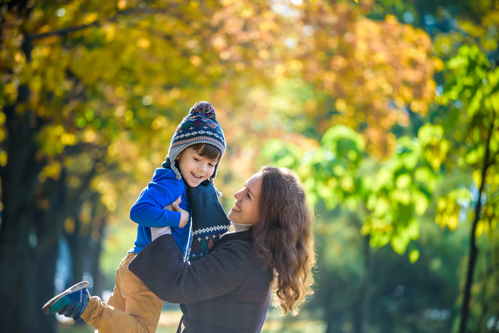 Madre jugando con su hijo en un parque en otoño.