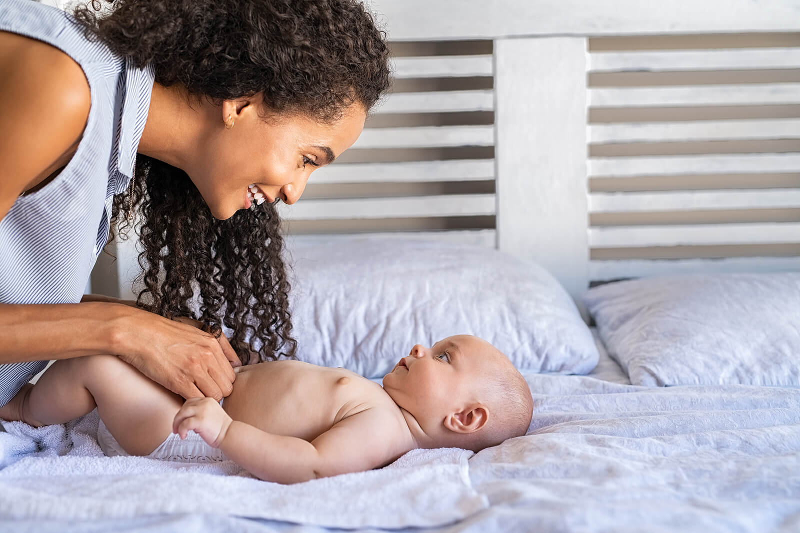 A mother talking to her baby while she changes his diaper.