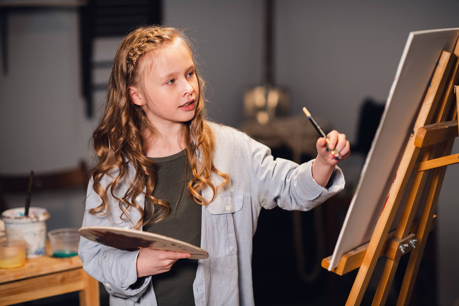 En ung flicka som målar på ett stativ.