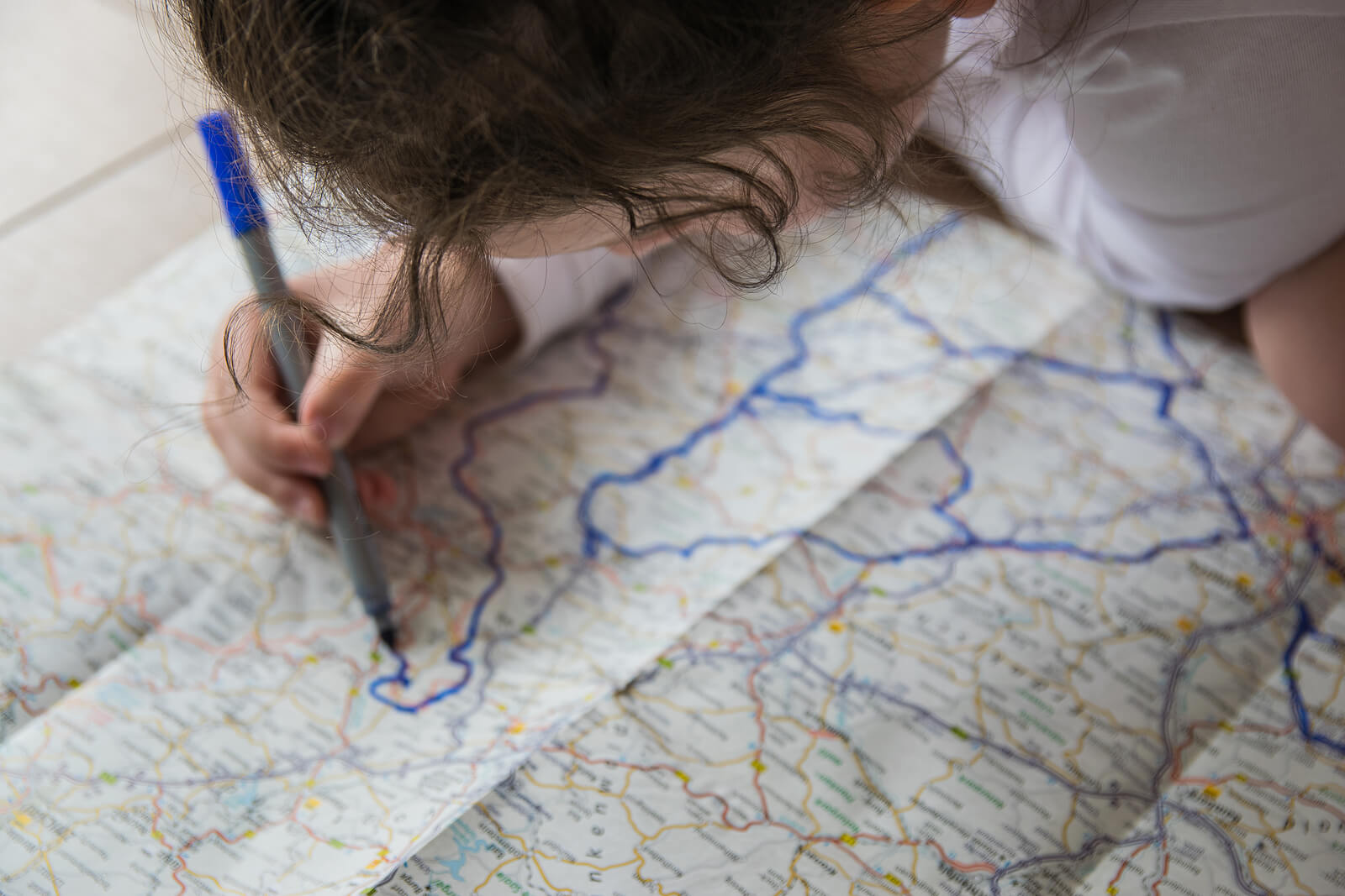 Niña trazando una ruta en un mapa.