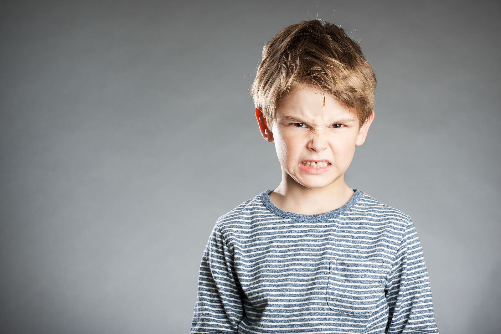 Niño enfadado porque desafía a sus padres y estos usan las estrategias.