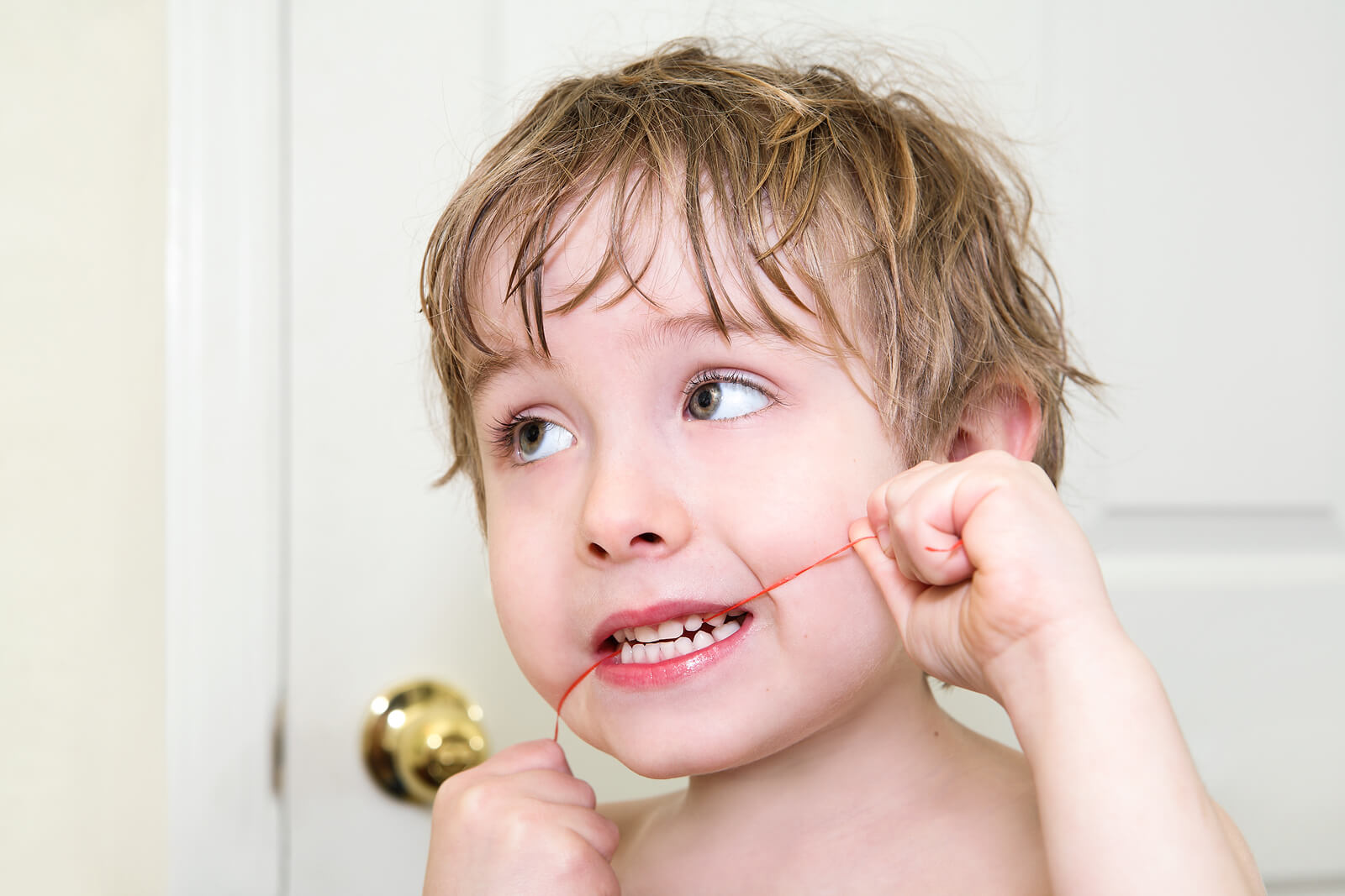 Enfant utilisant du fil dentaire.