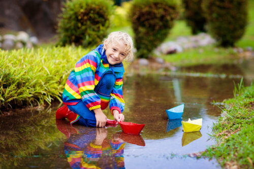 Niño practicando el juego con agua y unos barquitos de papel.