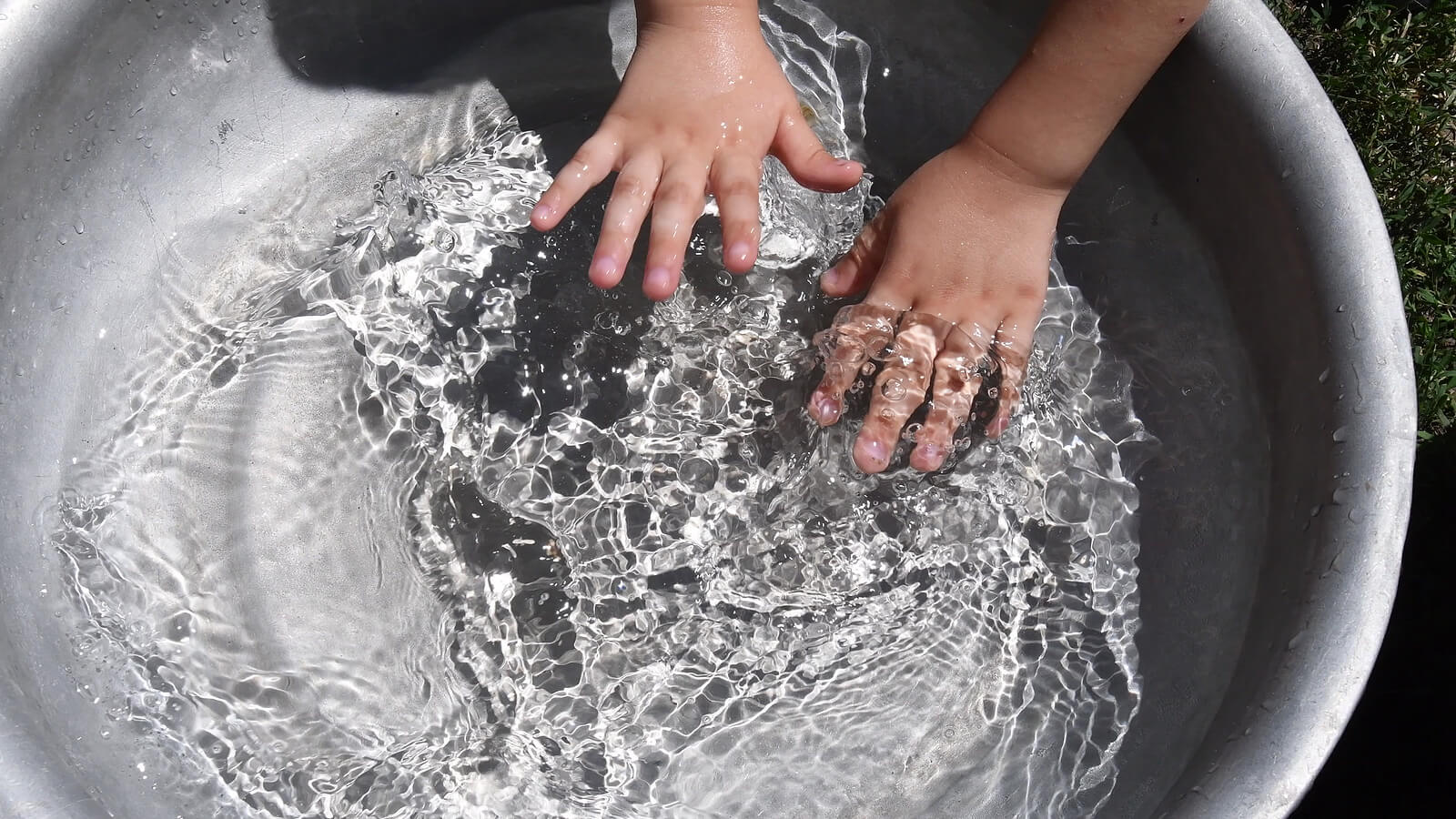 Niño jugando con agua en un barreño.
