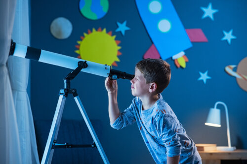 Niño mirando el espacio con un telescopio.