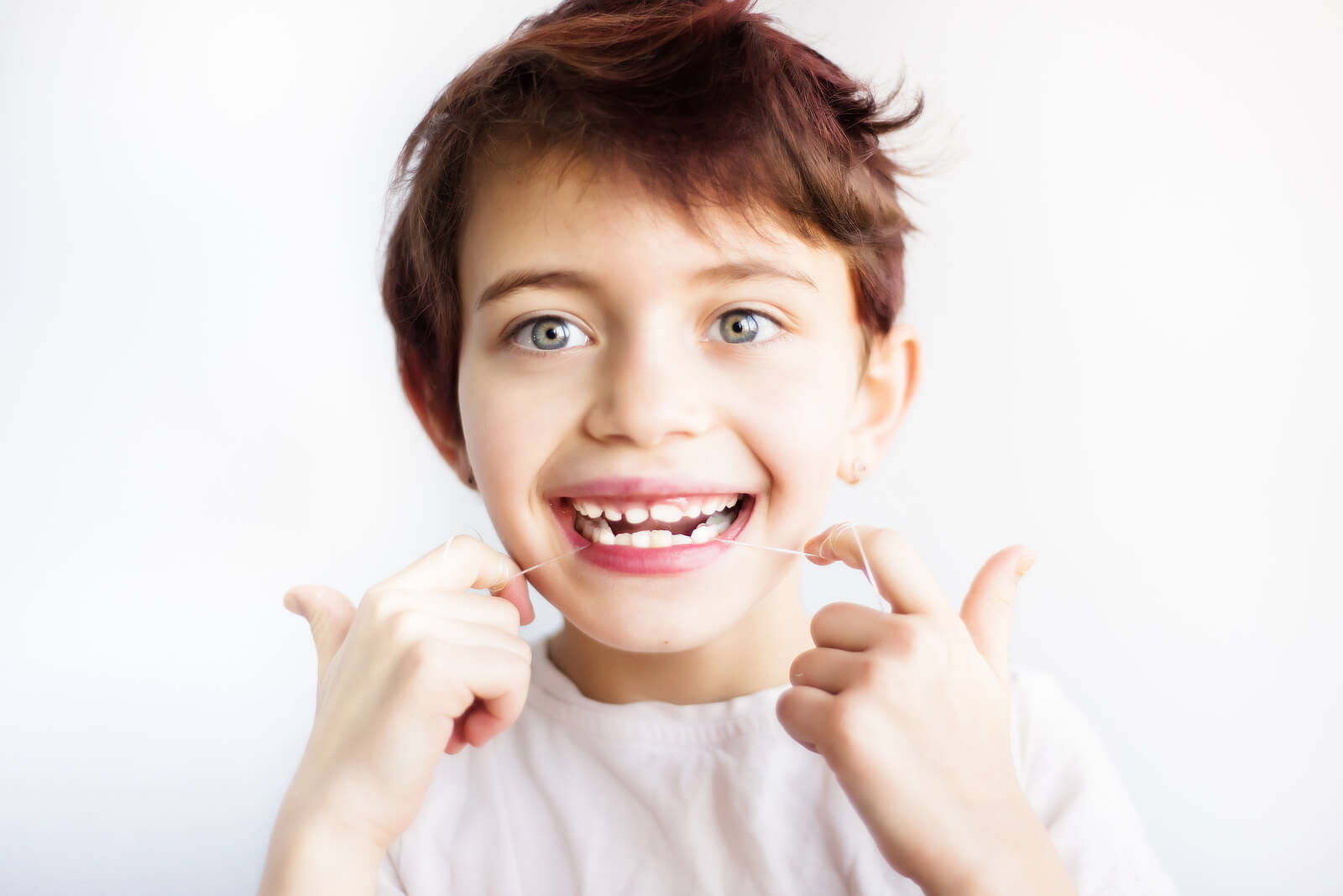 Enfant utilisant du fil dentaire pour l'hygiène buccale.