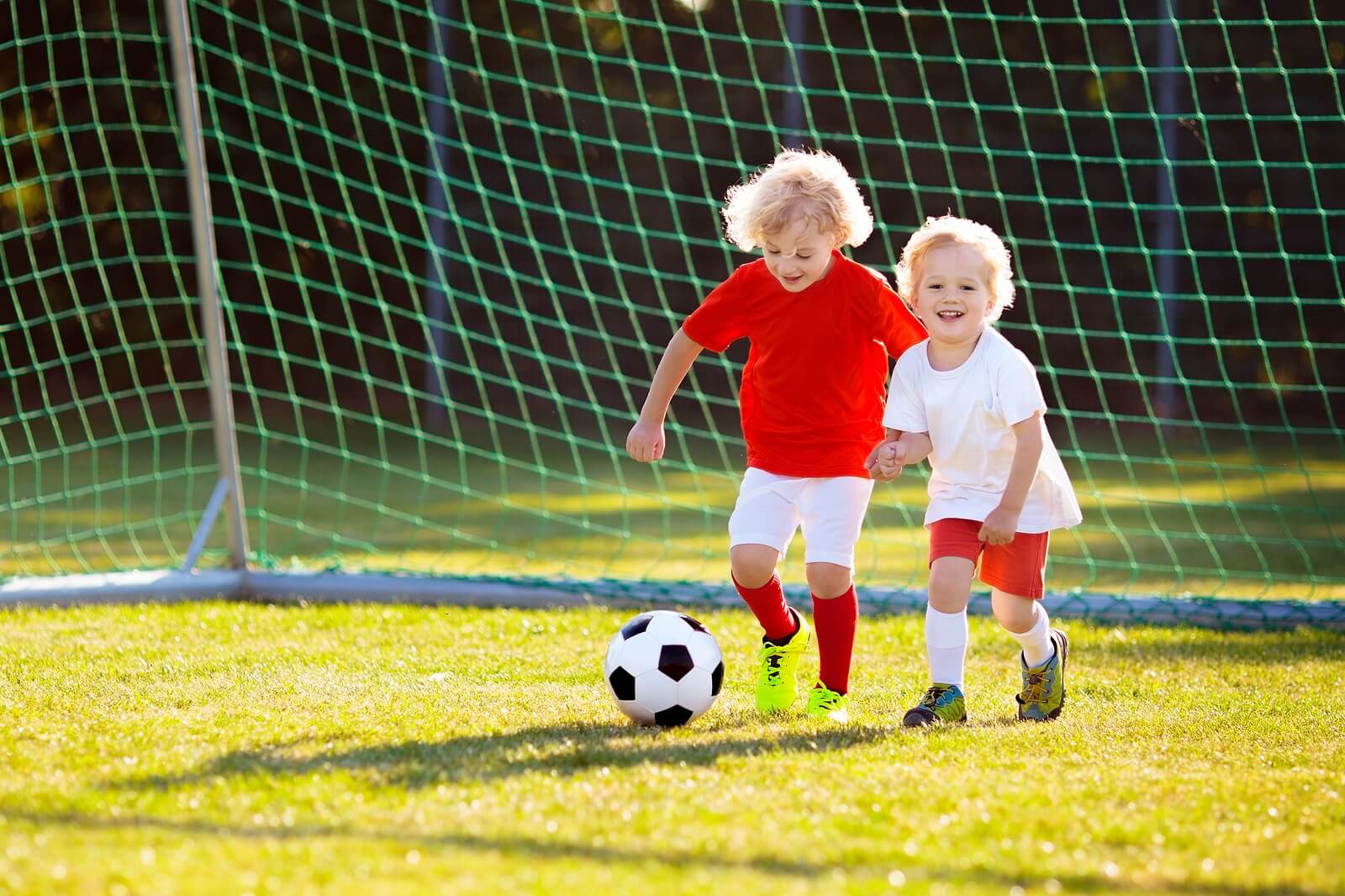Niños felices jugando al fútbol porque sus padres tienen un papel importante en el deporte infantil.