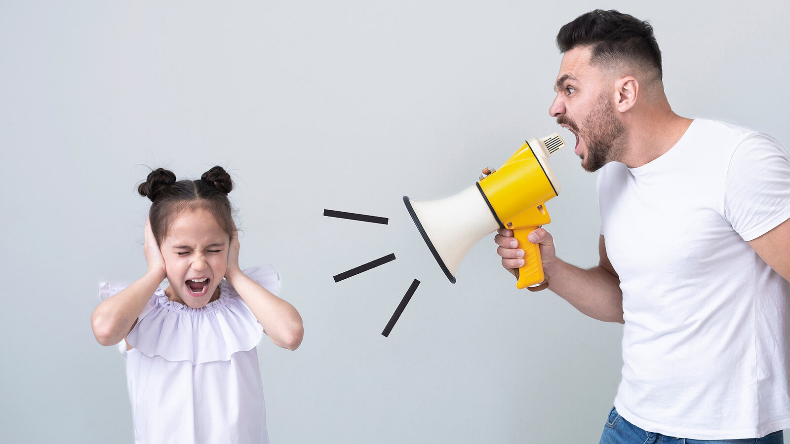 A father shouting at his daughter with a megaphone while she covers her ears.