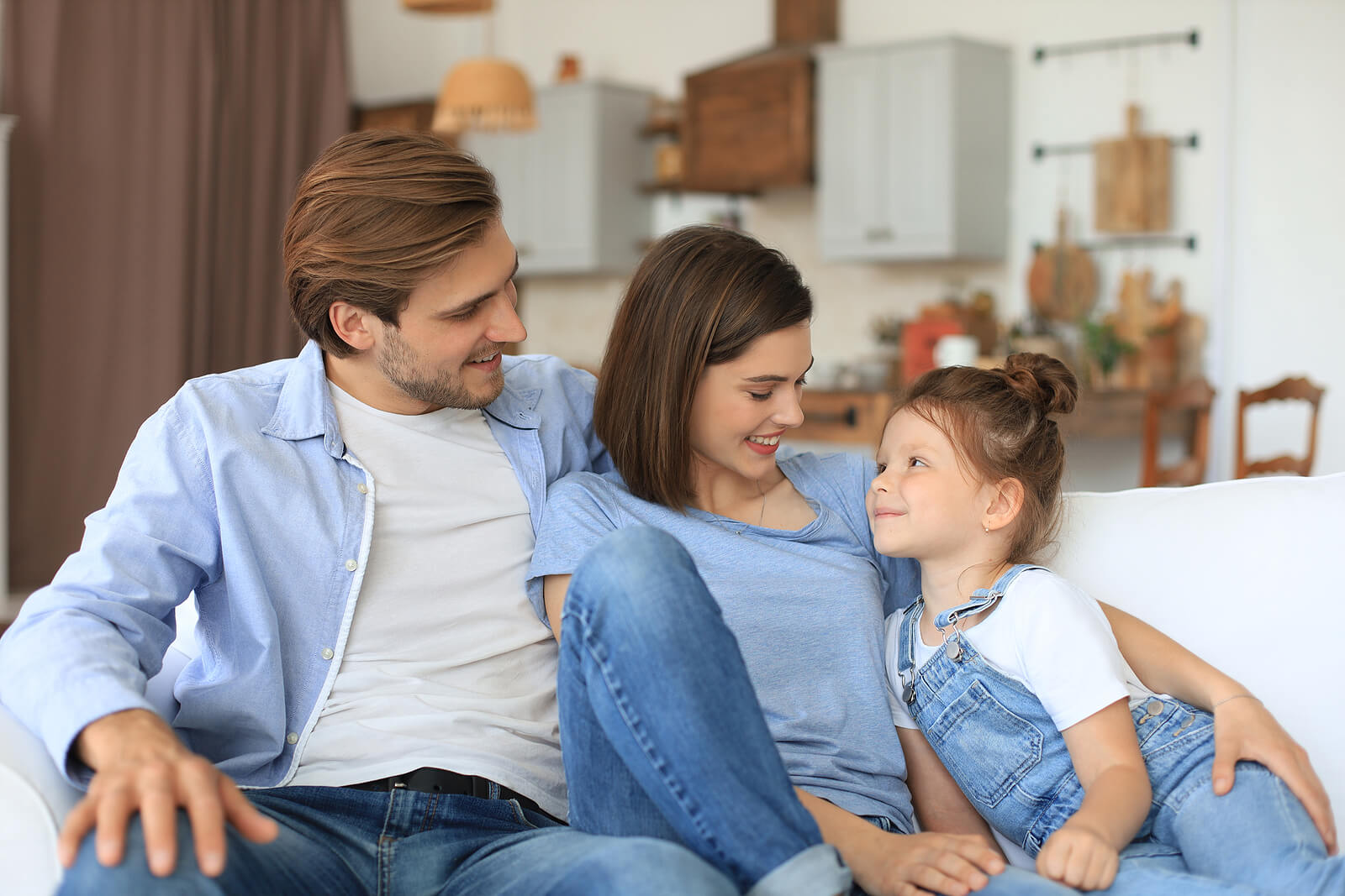 Deux parents avec leur fille sur un canapé.