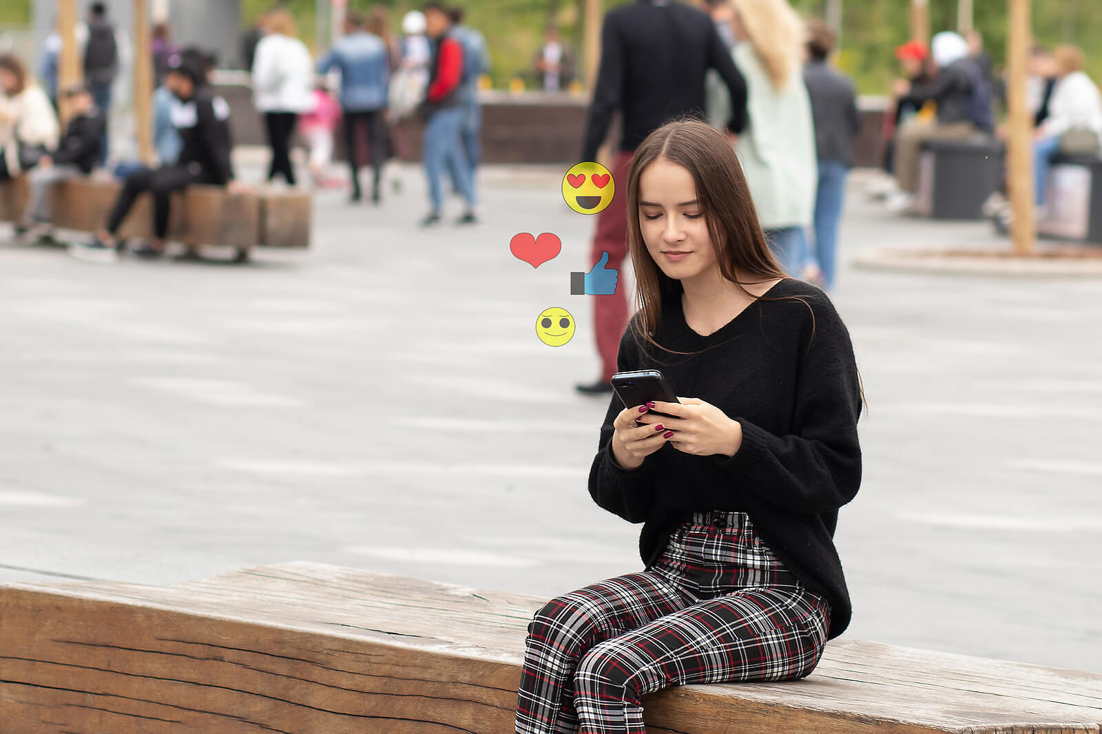 A teen sitting on a bench looking at social media.