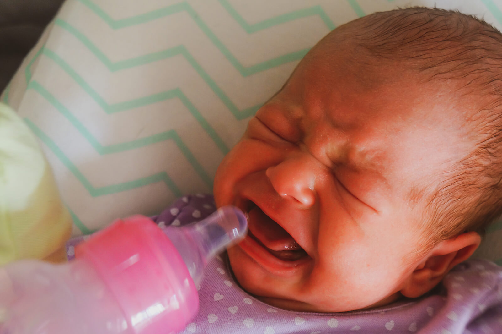 Bebé con síndrome de abstinencia neonatal llorando mientras come.