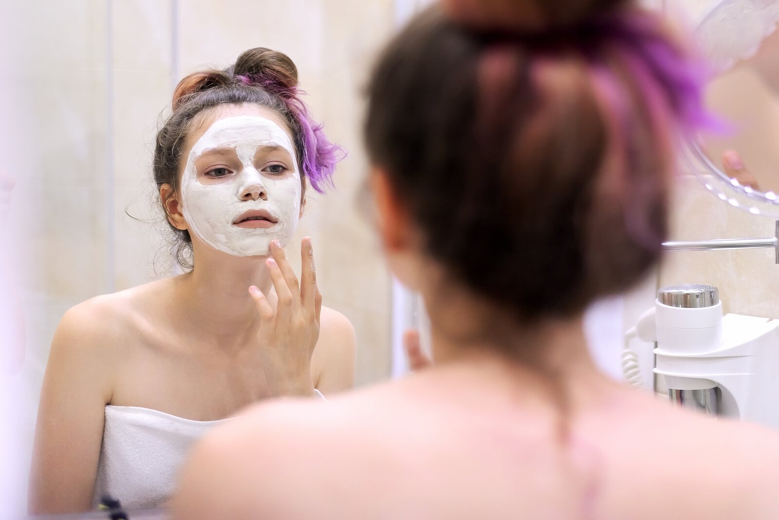 Chica aplicando una mascarilla facial para cuidar su piel en la adolescencia.