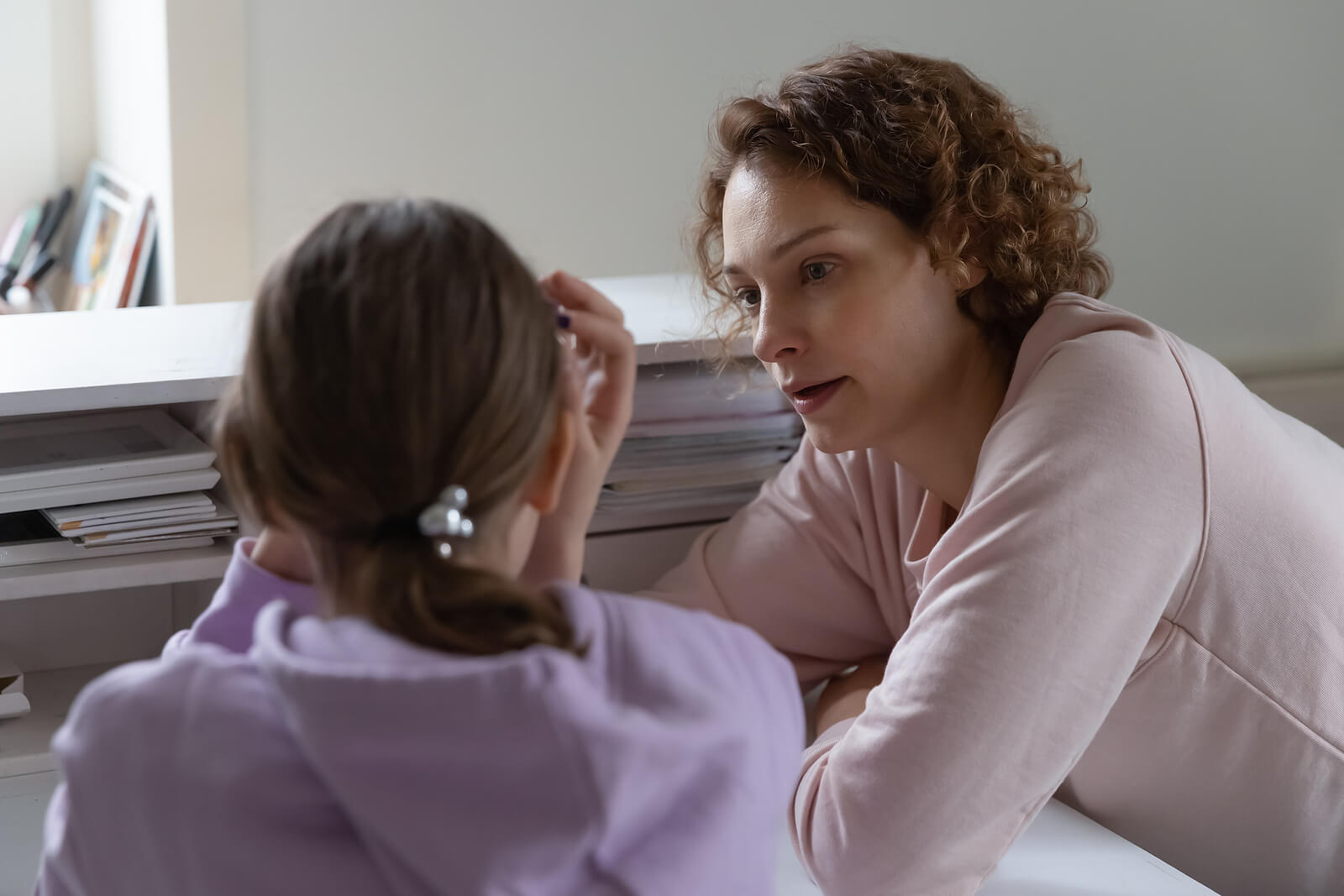 Madre intrusiva intentando hablar con su hija adolescente.