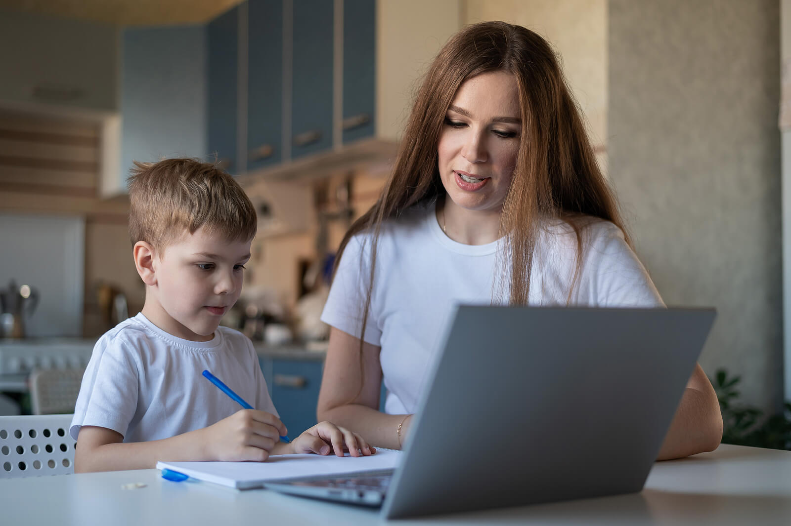 Mãe ajudando filho a estudar no computador.