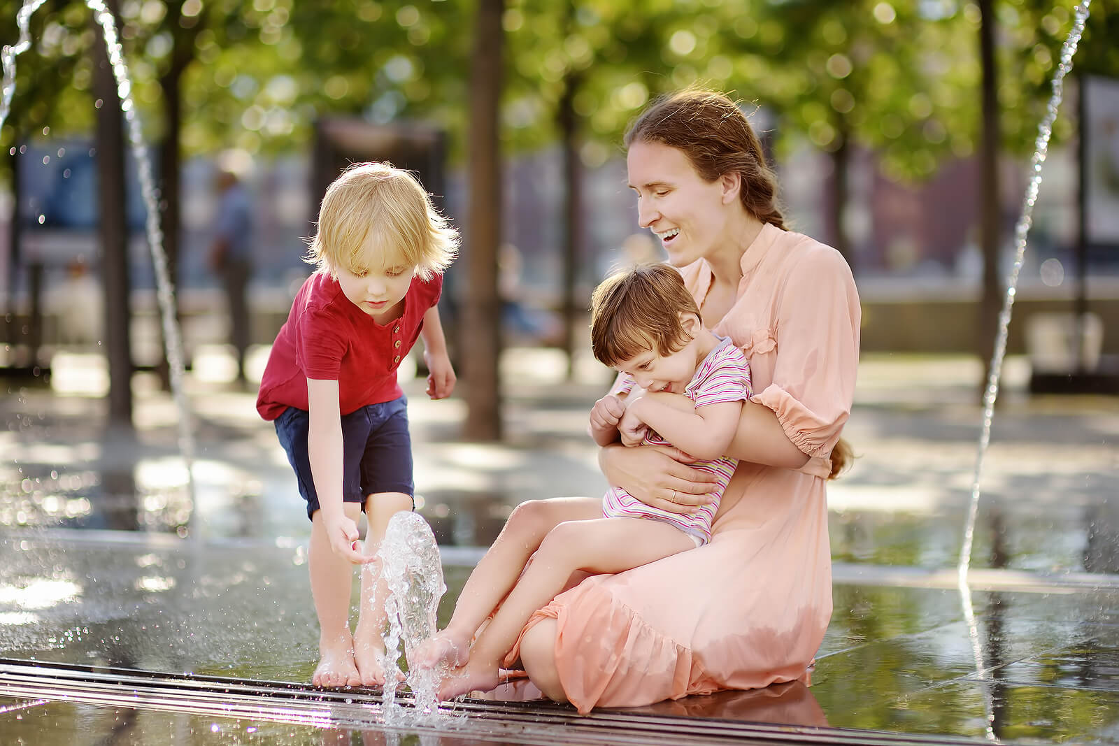 Mère jouant avec ses enfants à côté d'une fontaine.