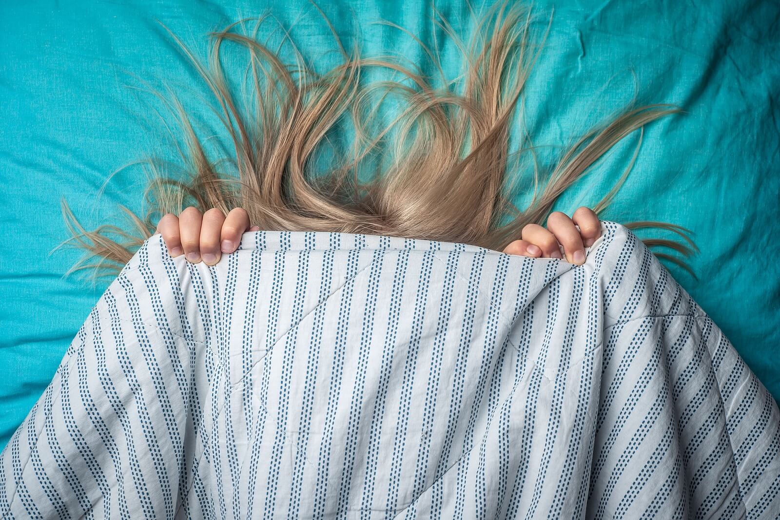 Une jeune fille qui se cache sous un drap. 