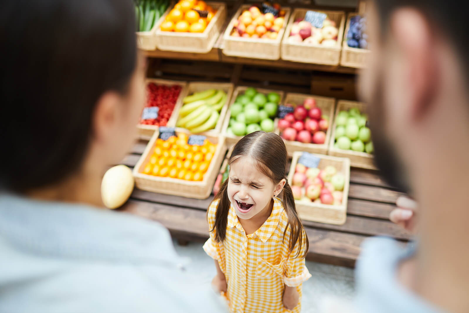 Niña con una rabieta en la frutería como parte de la etapa de los niños egocéntricos.
