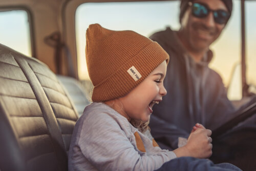 Niña riéndose con su padre en el coche.