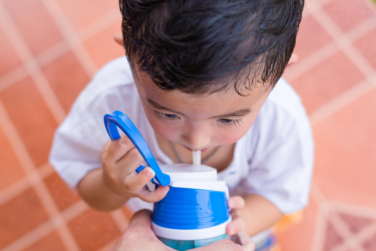 Un enfant qui boit de l'eau parce qu'il transpire.