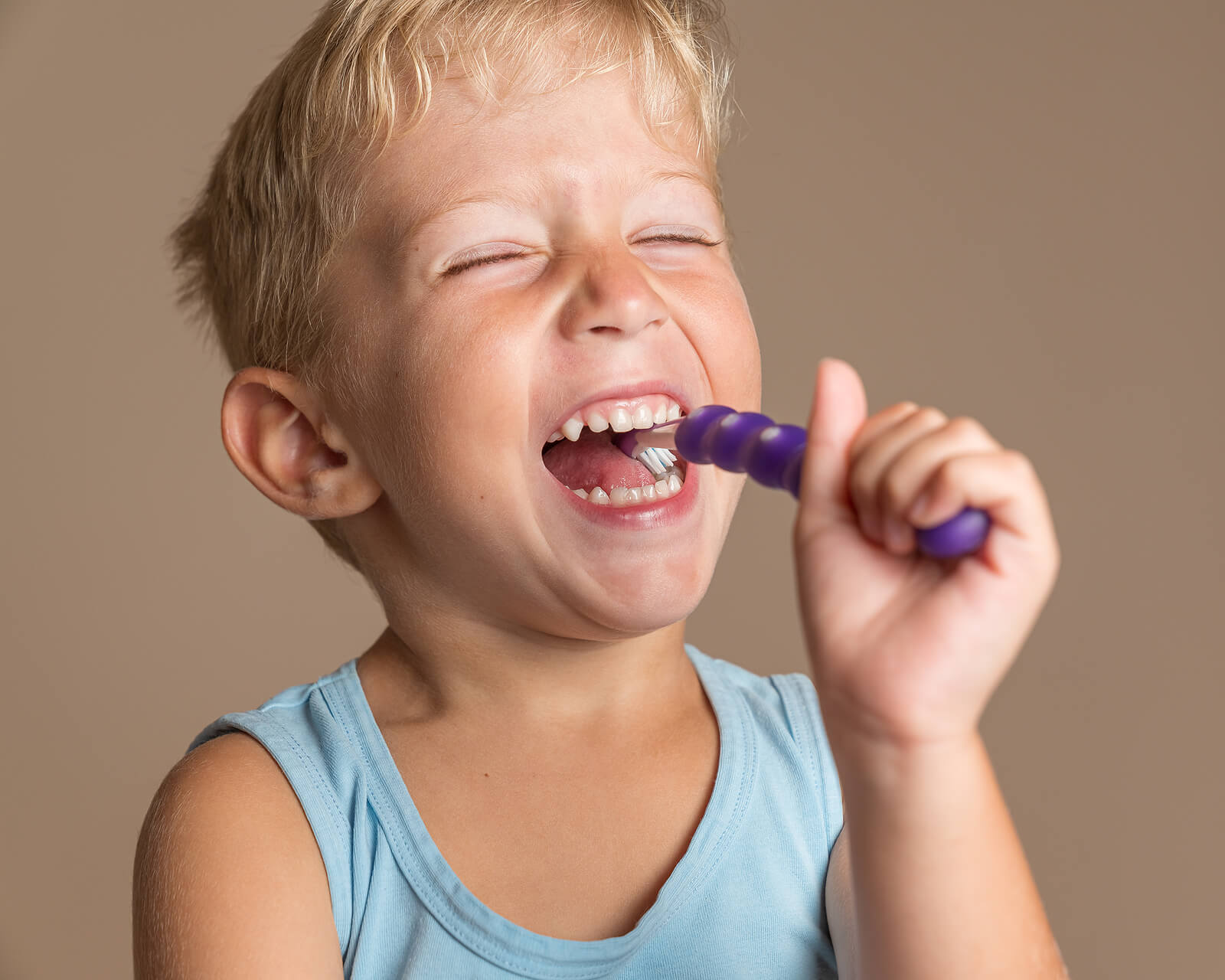 Niño cepillándose los dientes feliz con una pasta con flúor.