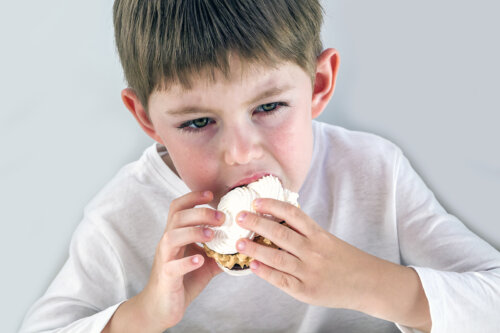 Niño con hambre emocional comiendo bollería industrial.