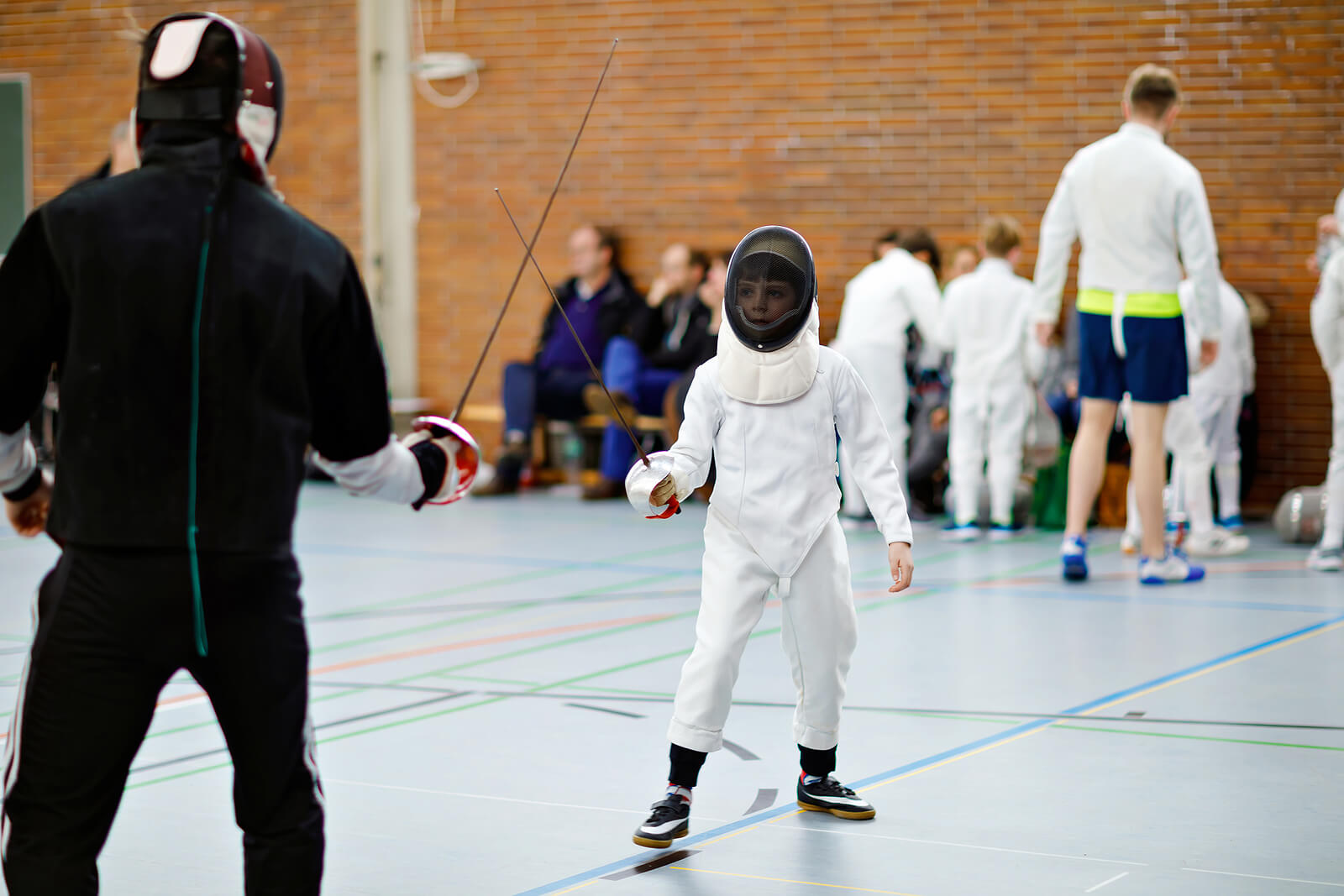 Niño en una competición de esgrima como deporte infantil.