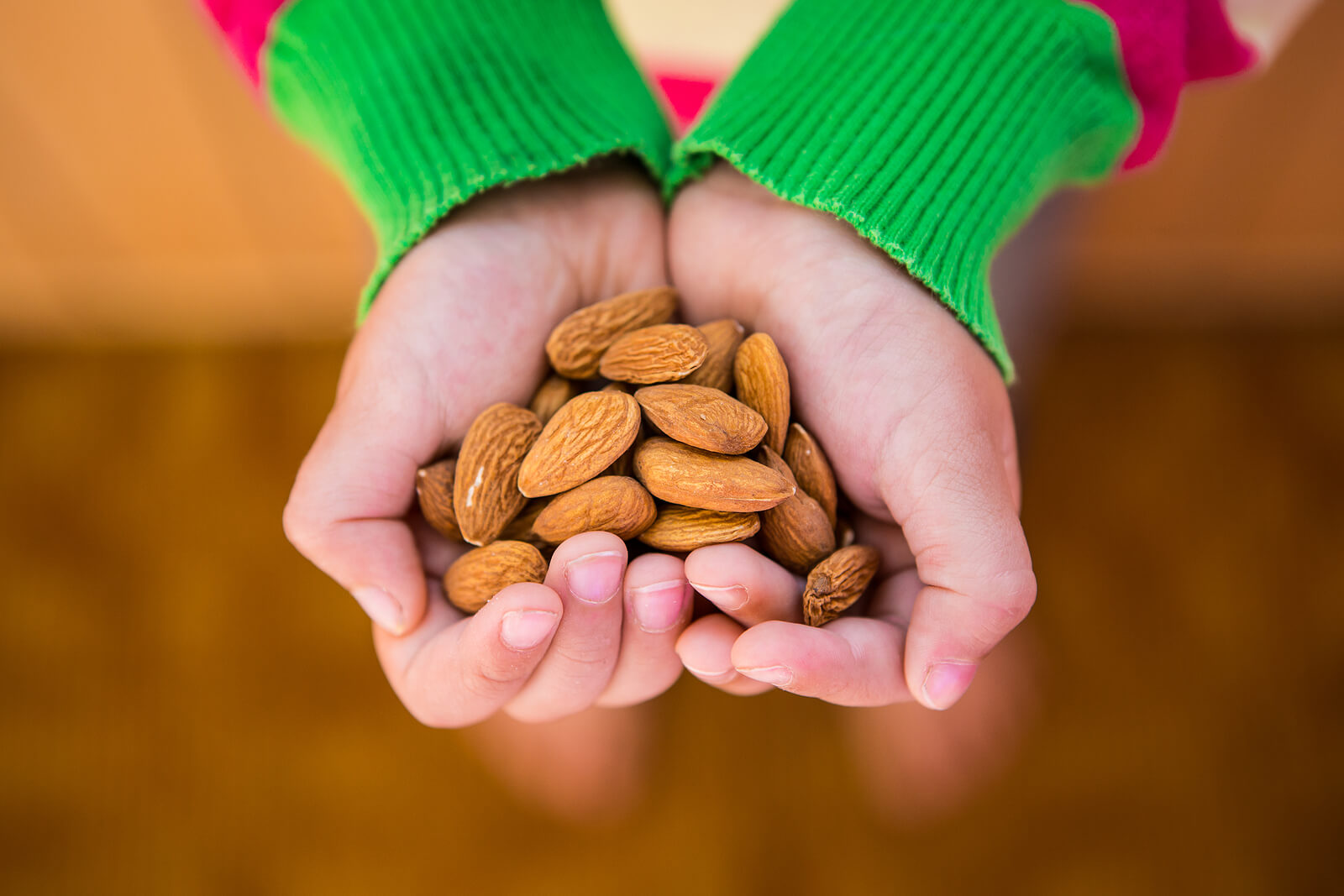A child holding a handful of almonds.