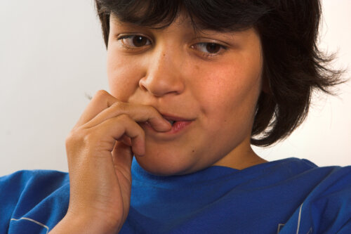 Niño mordiéndose las uñas nervioso por un examen.