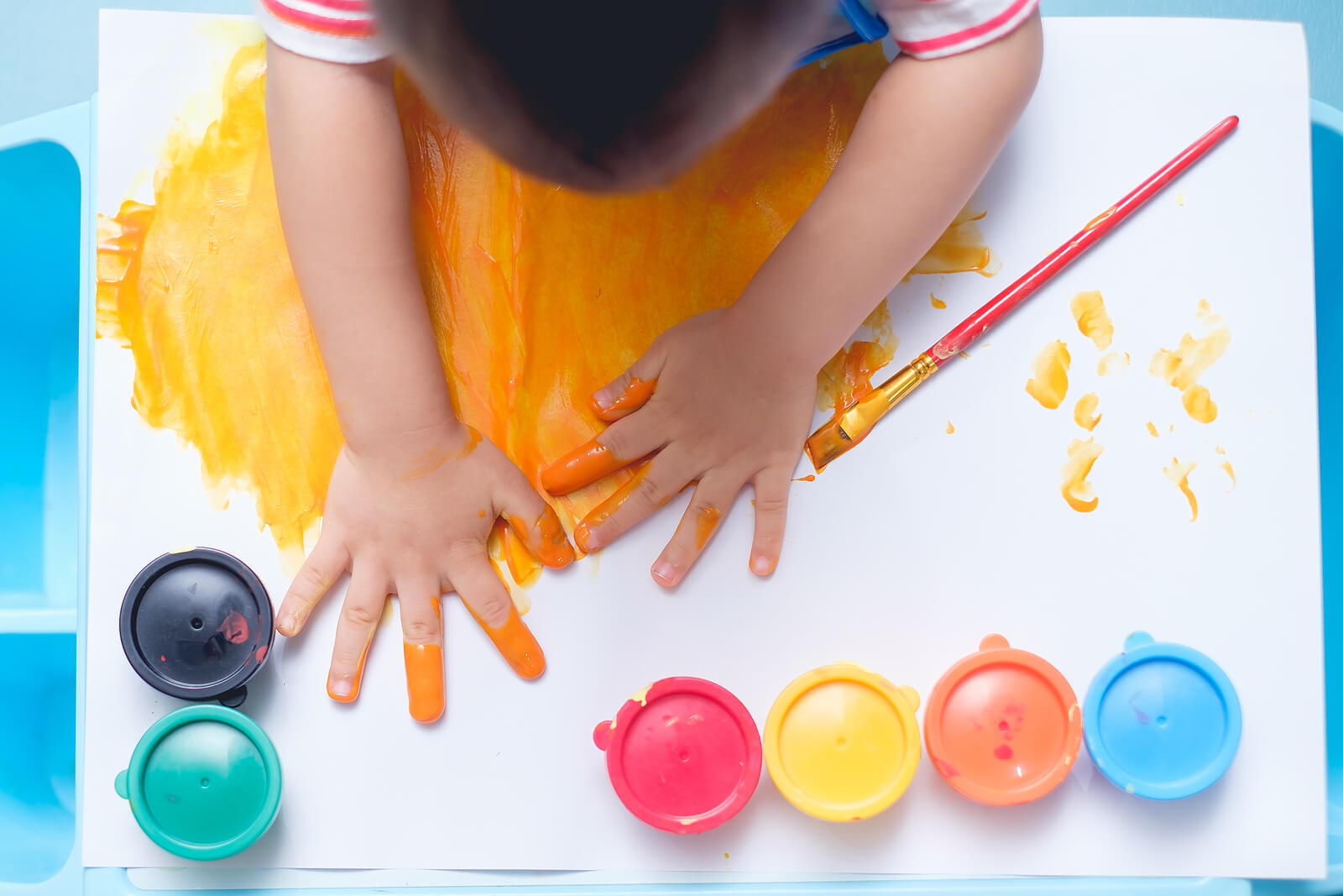 Niño pintando con las manos y los dedos.