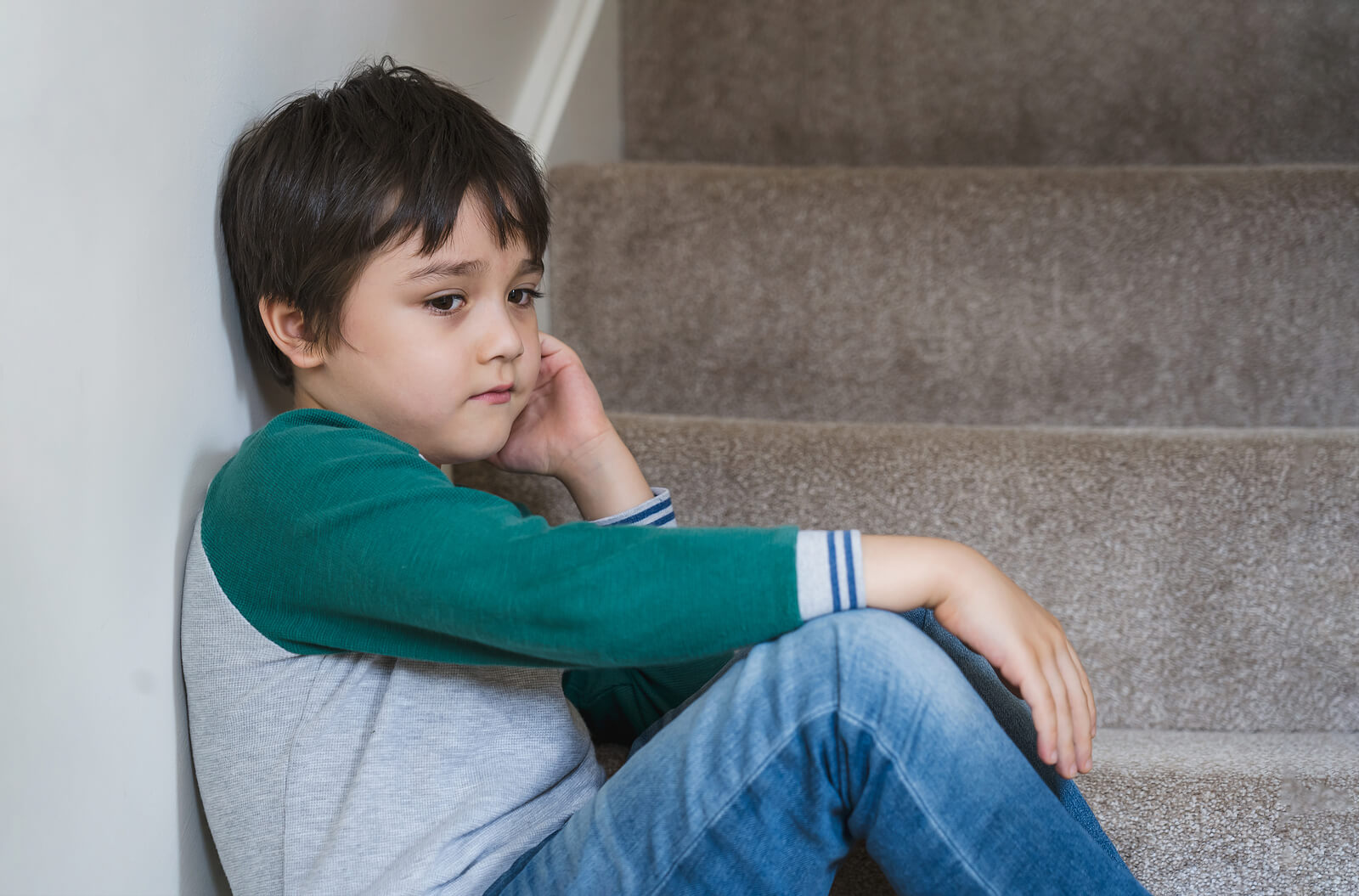 Enfant triste assis dans les escaliers.