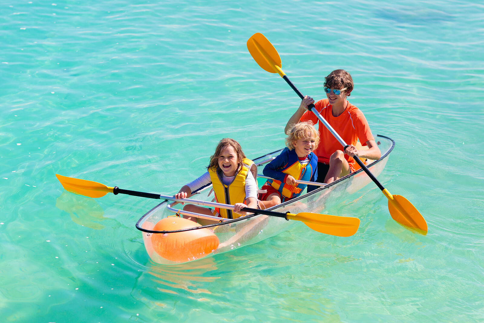 Children rowing in a transparent boat.