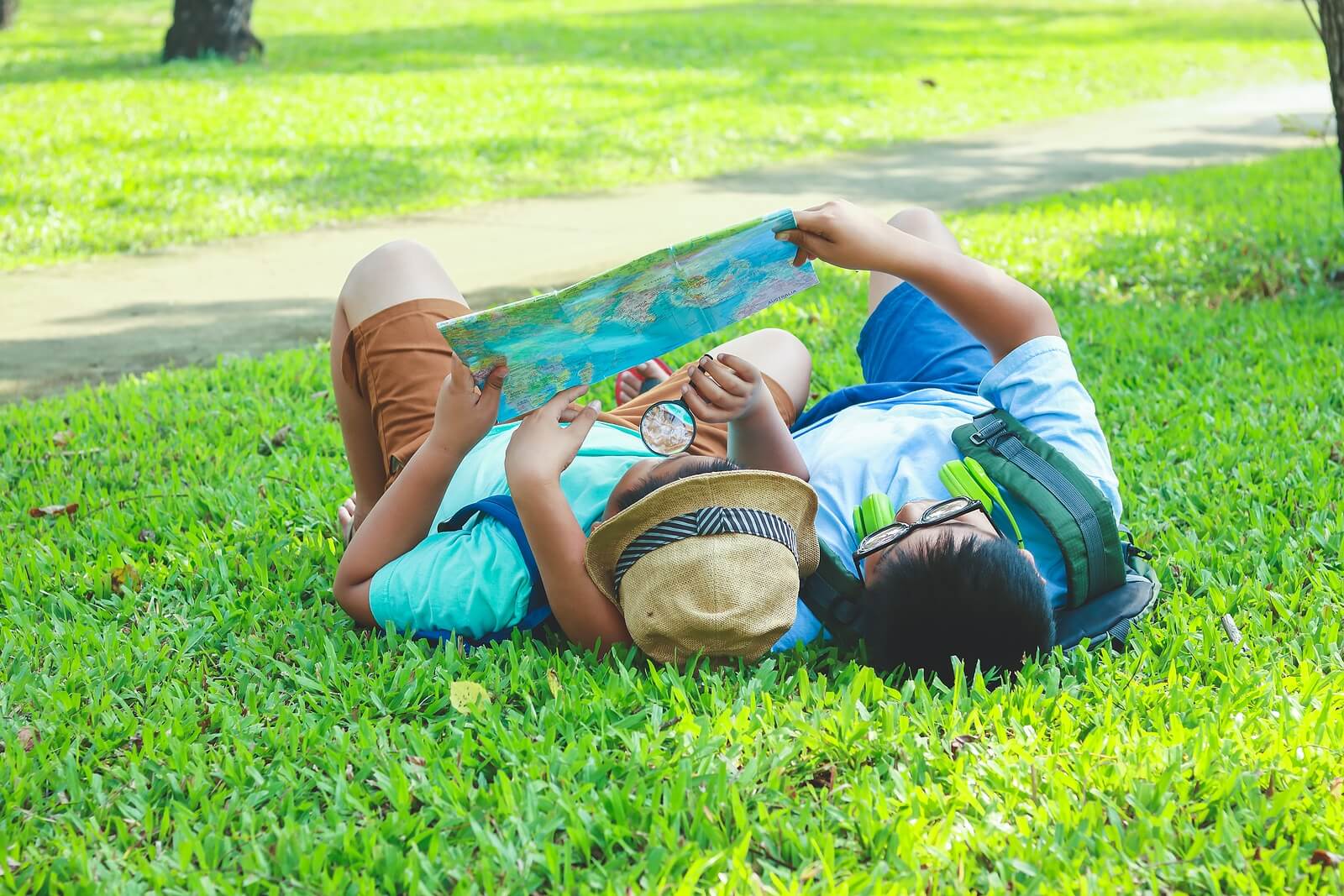 Niños mirando un mapa tumbados en el césped.