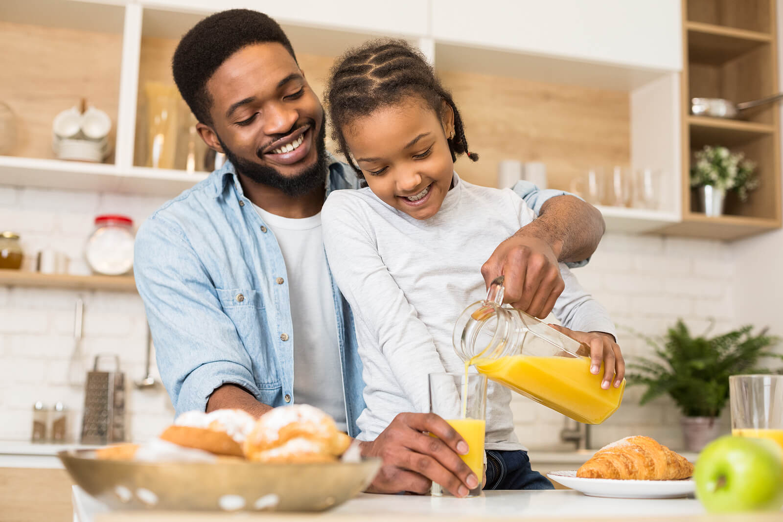 Un père qui sert un jus d'orange à sa fille.
