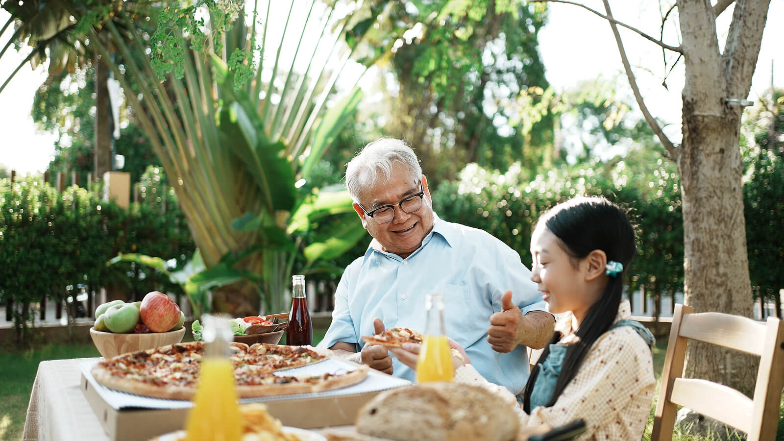 Abuelo con su nieta comiendo pizza.