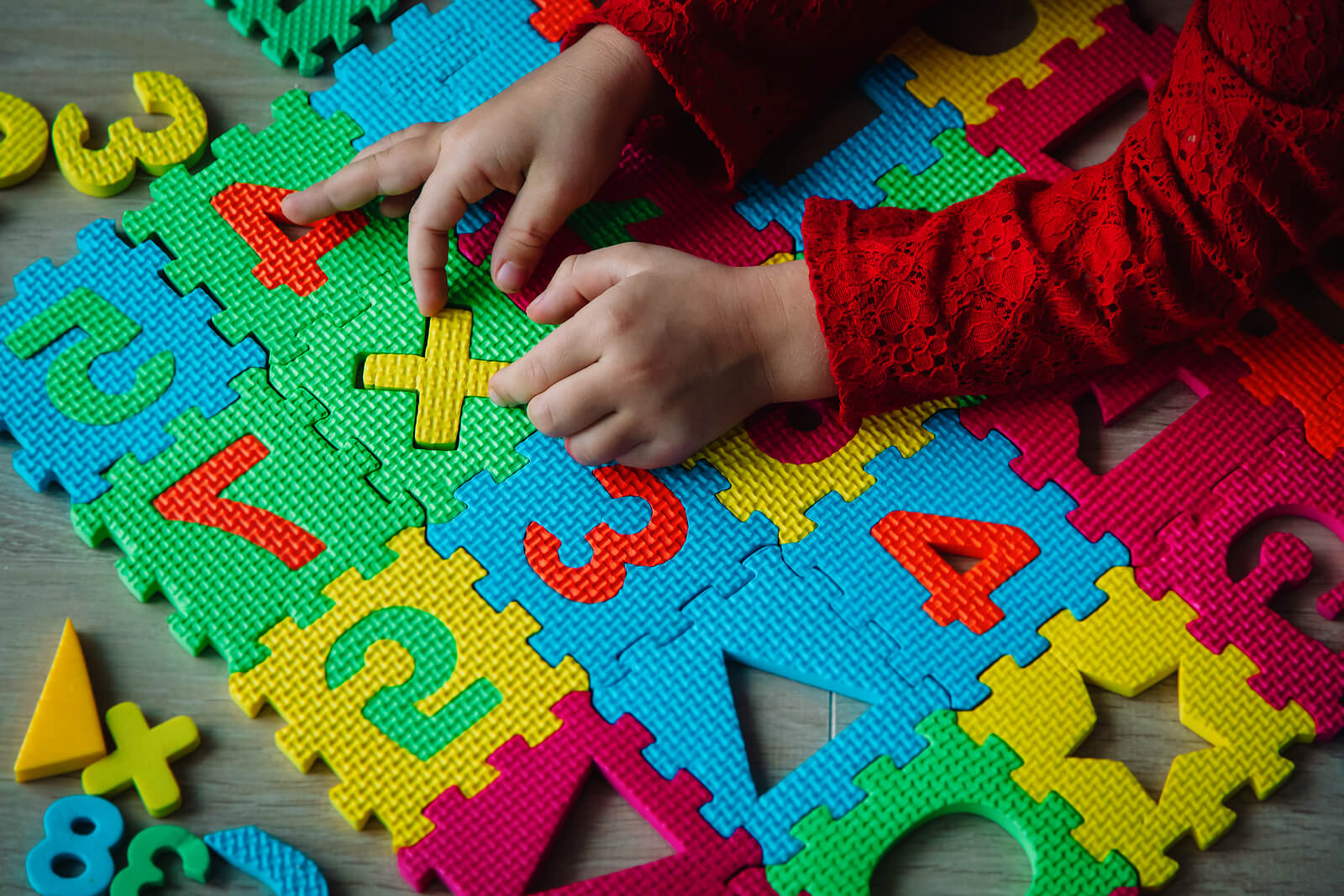 Niño jugando en una alfombra con números porque saber contar no implica conocerlos.