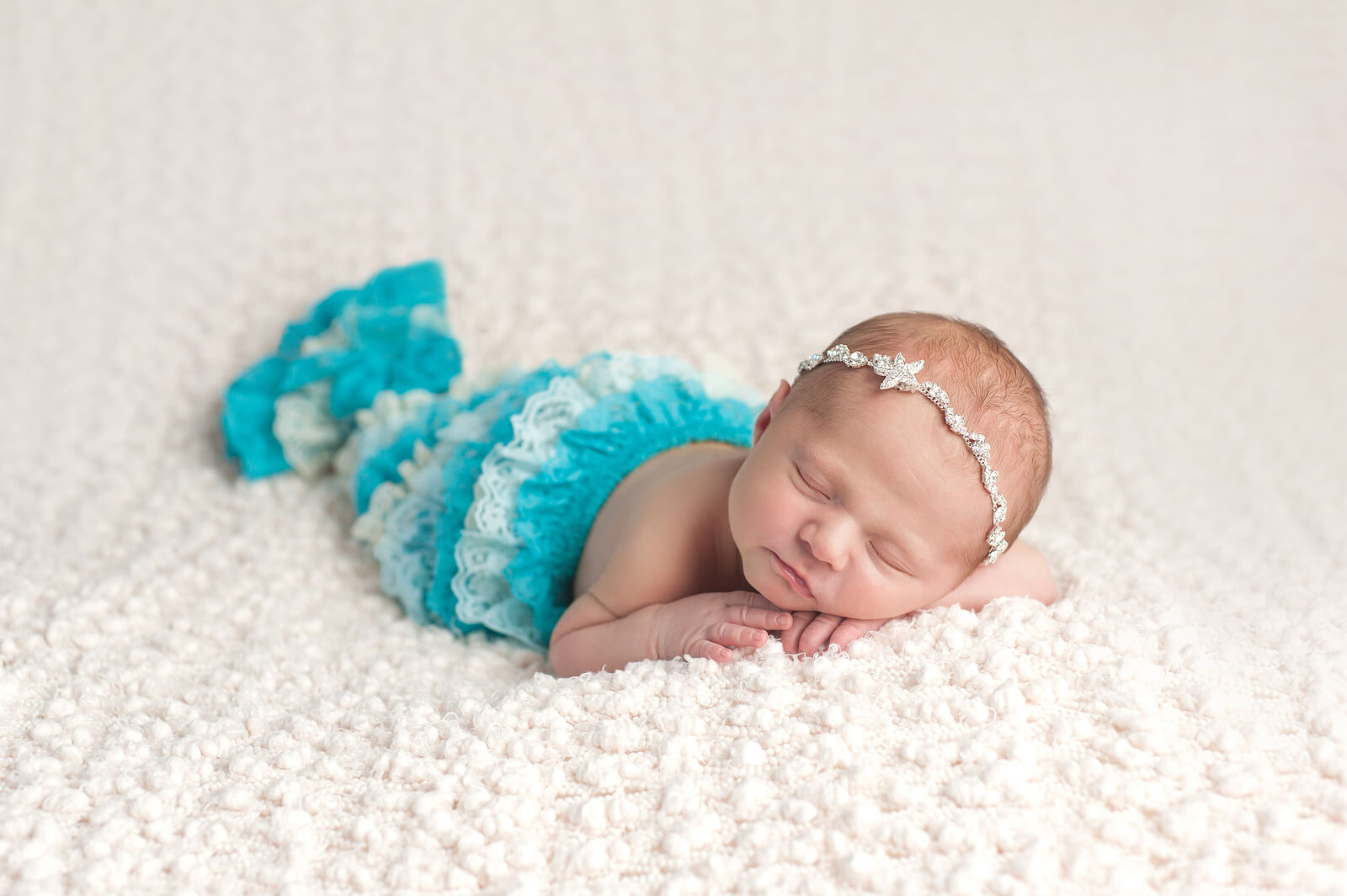A newborn baby girl dressed as a mermaid.