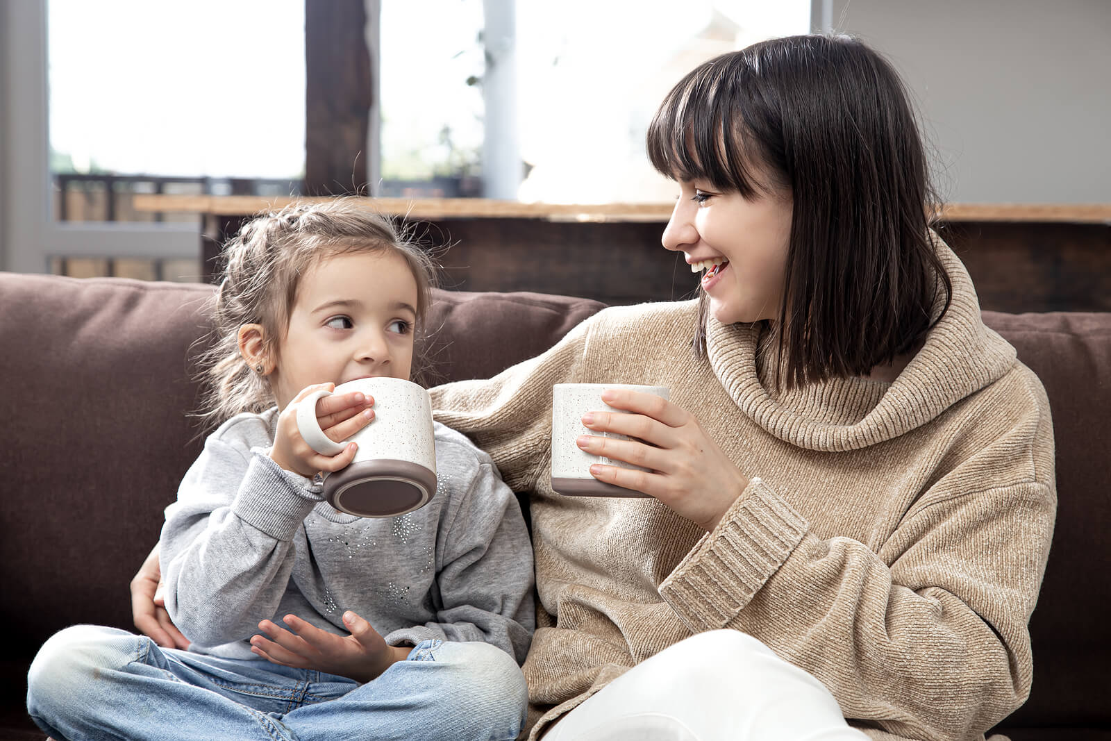 Madre hablando con su hija sobre cómo le ha ido el cole mientras beben chocolate.