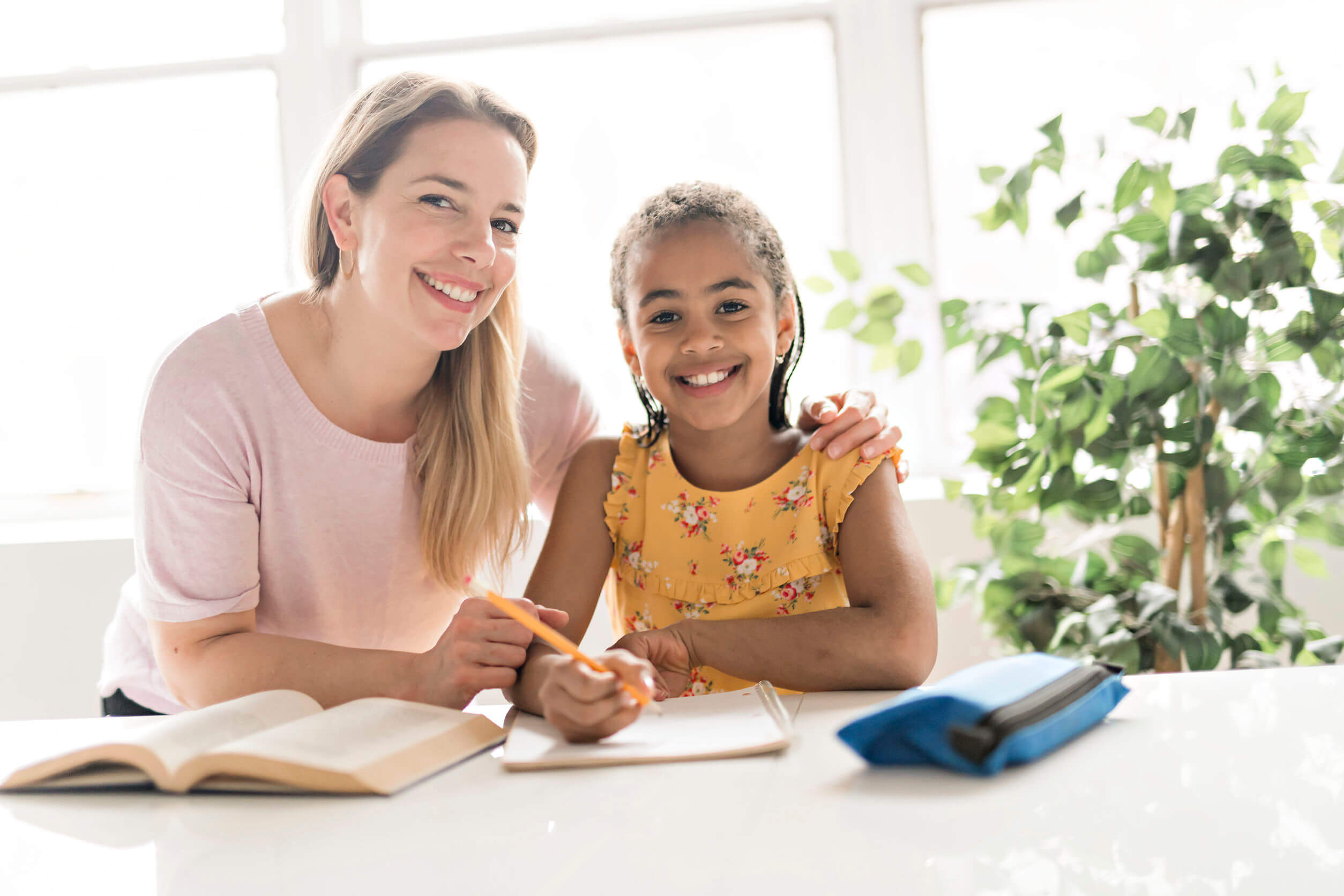 Madre motivando a su hija a escribir historias.