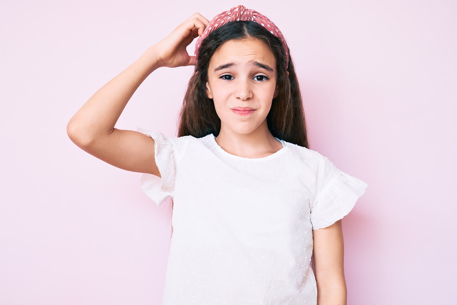 Niña insegura rascándose la cabeza.