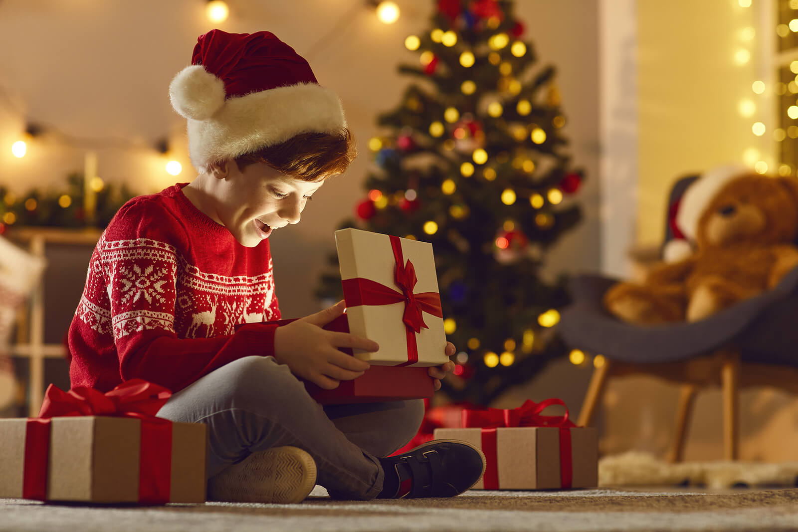 Bambino che apre i suoi regali di Natale con entusiasmo.