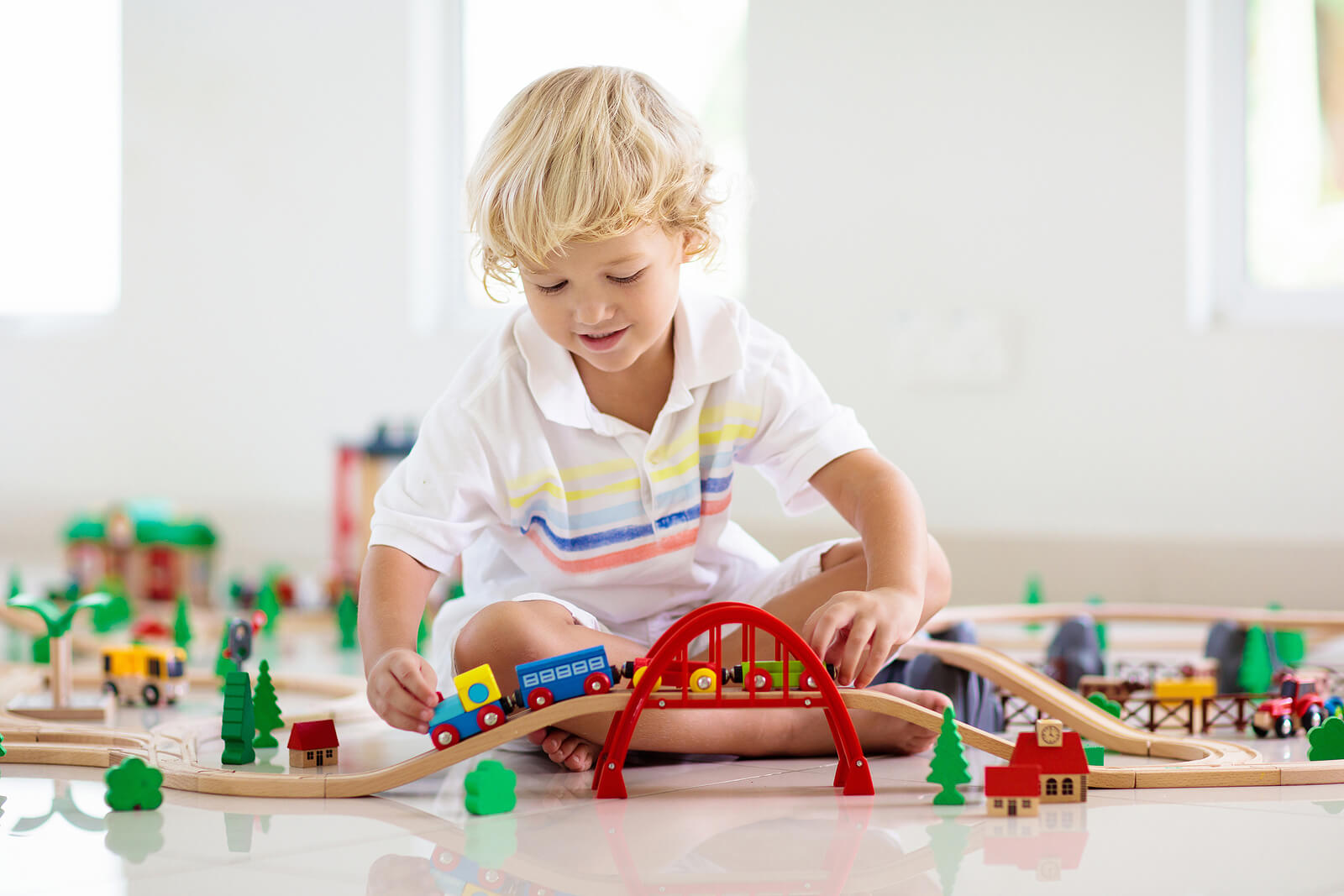 Niño jugando con trenes de madera.
