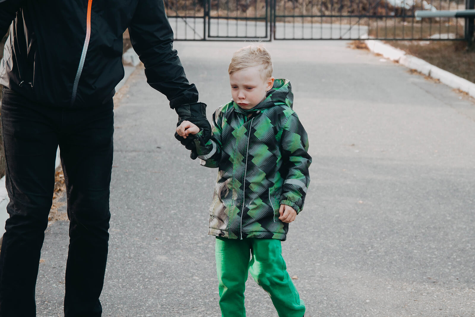 Niño llorando triste de la mano de su padre.